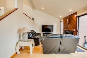 Una sala de estar moderna con sofá, televisión y chimenea.