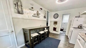 A modern kitchen with a dark wooden bar, white cabinets, and a blue rug. - Gorgeous 2 bedroom in little Bohemian Omaha (Omaha)