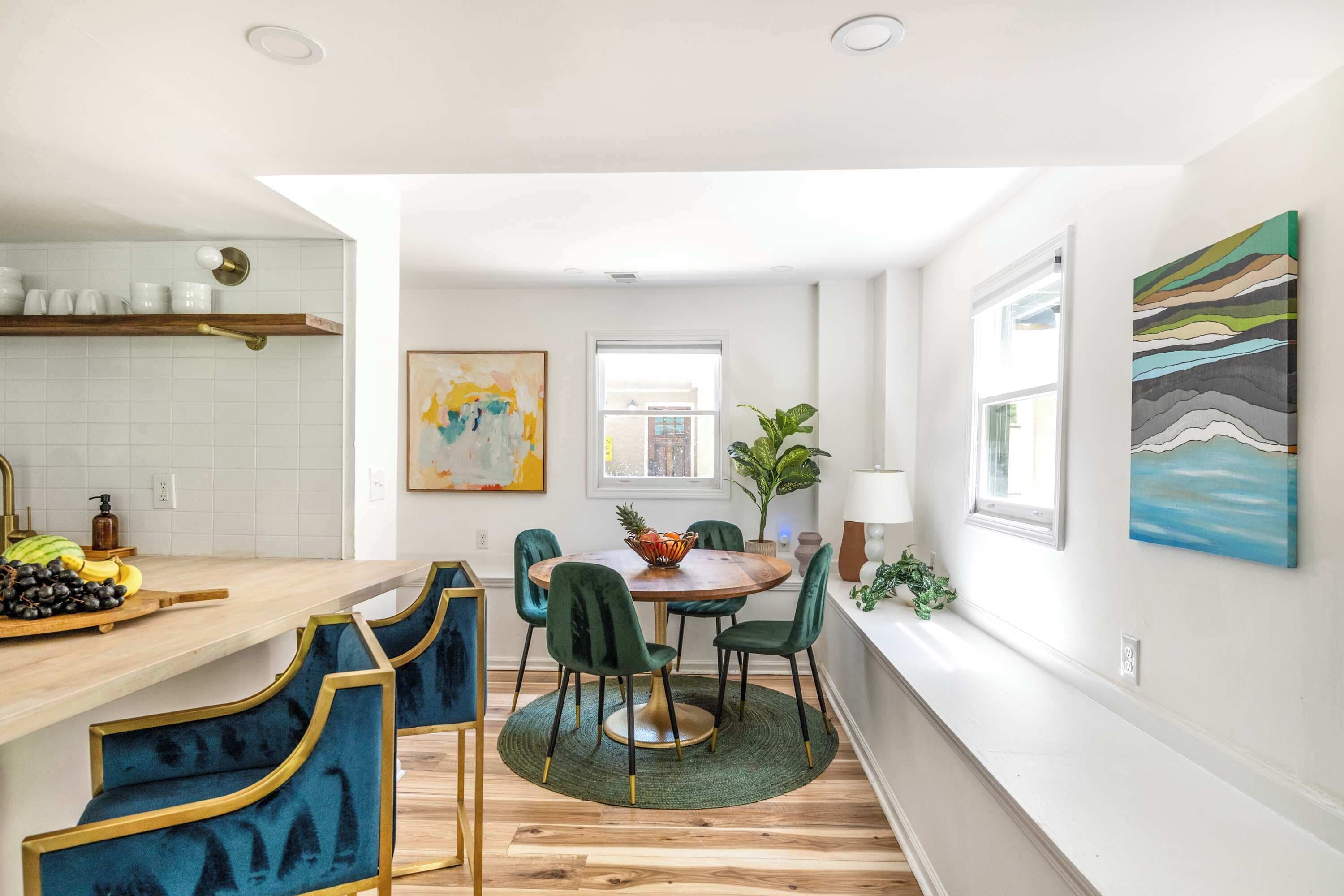 A modern kitchen with a wooden countertop, a dining table with chairs, and a green rug.
