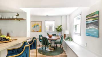A modern kitchen with a wooden countertop, a dining table with chairs, and a green rug.