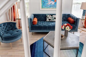 A modern living room with a blue sofa, a tufted armchair, and a geometric coffee table. - Brooklyn Bungalow (Atlanta)