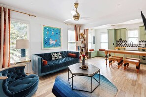 A modern living room with a blue sofa, a coffee table, and a dining area with a wooden bench. - Brooklyn Bungalow (Atlanta)