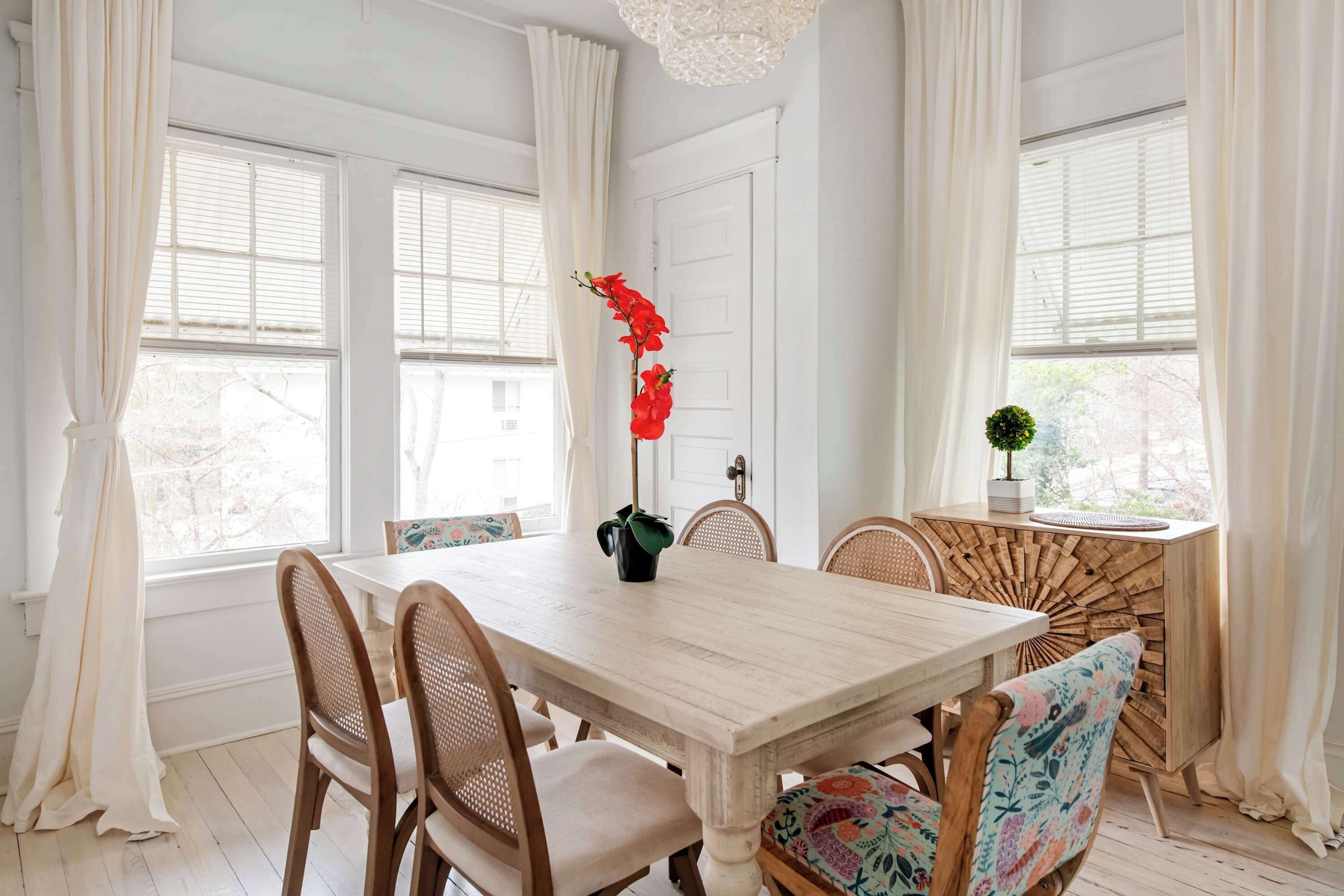 A dining room with a wooden table, four chairs, and a decorative plant.