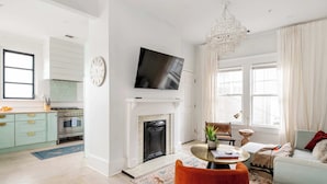 A modern living room with a fireplace, a television, and a dining area with a table and chairs. - Lace and Leather (Atlanta)