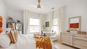 A bedroom with a bed, a desk, a dresser, and a ceiling fan. - Lace and Leather (Atlanta)