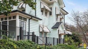 A two-story house with a balcony, a black metal fence, and a tree in the foreground. - Lace and Leather (Atlanta)