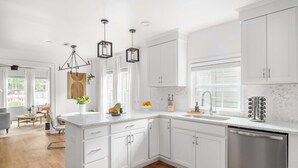 Una cocina moderna con armarios blancos, una isla central y un lavavajillas de acero inoxidable.