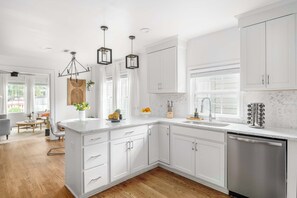 A modern kitchen with white cabinetry, a central island, and a stainless steel dishwasher. - A Hard Day's Night (Atlanta)