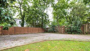 A backyard with a wooden fence, a grassy area, and trees.