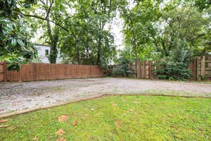Un jardin avec une clôture en bois, une pelouse et des arbres.