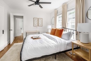 A bedroom with a bed, bedside tables, a ceiling fan, and a window with curtains.