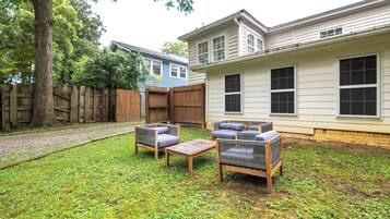 A backyard with a wooden deck, two gray sofas, and a small table.