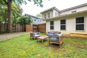 A backyard with a wooden deck, two gray sofas, and a small table. - A Hard Day's Night (Atlanta)