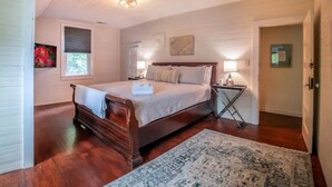 Une chambre à coucher avec un lit en bois, une table de chevet, une commode, un tapis et une fenêtre donnant sur un beau paysage.