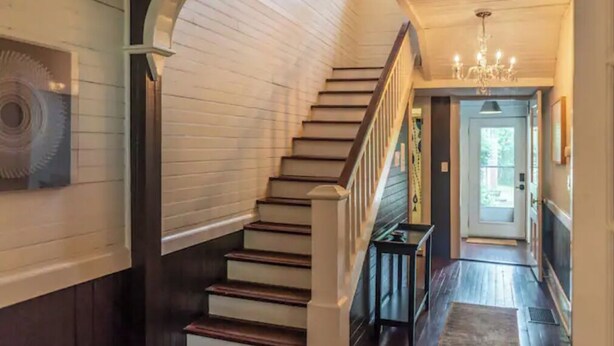 Un escalier en bois, muni d’une rampe, mène à une porte située en haut.