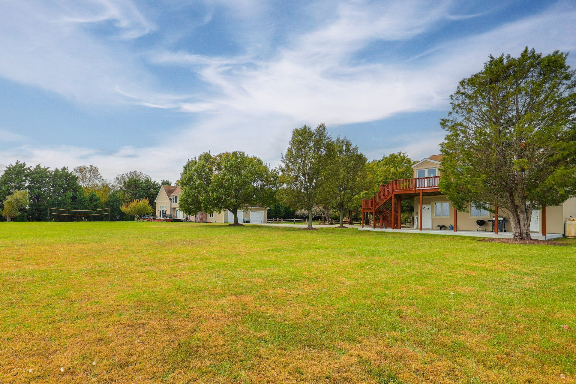A residential area with houses, a large grassy field, and trees.