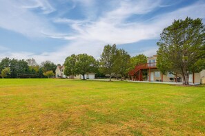 A residential area with houses, a large grassy field, and trees.