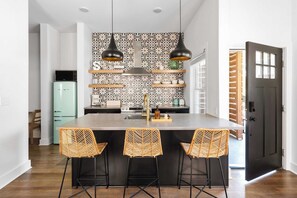 Een moderne keuken met een centraal eiland, hanglampen en een achterwand met patroon.