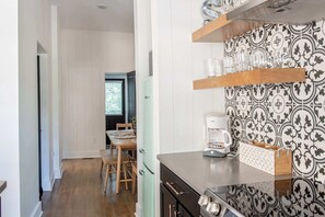 A kitchen with a coffee maker, a wooden table, and chairs.