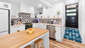 A modern kitchen with white cabinets, a wooden countertop, and a patterned backsplash. - The Fox Den (Atlanta)