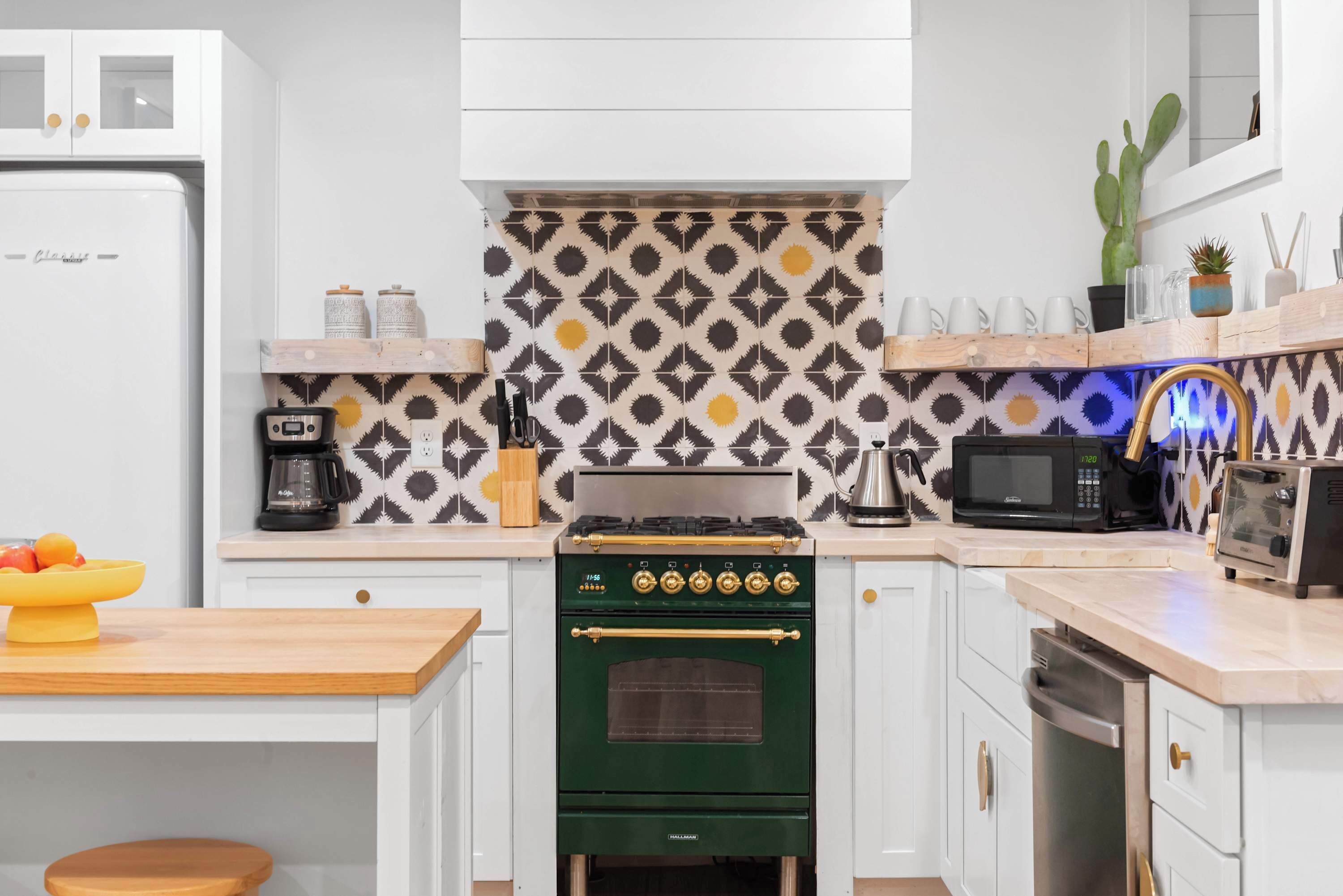 A kitchen with white cabinets, a green oven, a microwave, and a coffee maker.