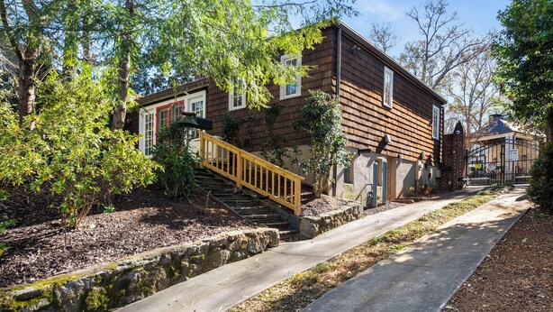Une maison en bois à deux étages, avec un escalier en bois menant à l’entrée.
