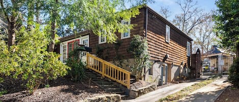 A two-story wooden house with a wooden staircase leading to the entrance.
