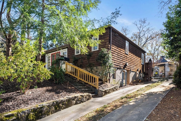 A two-story wooden house with a wooden staircase leading to the entrance.