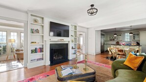 Amplia sala de estar con chimenea, televisor y comedor con sillas y una mesa.