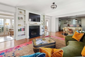 A spacious living room with a fireplace, a television, and a dining area with chairs and a table.