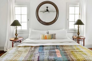 A bedroom with a bed, two bedside tables with lamps, a ceiling fan, and a window with curtains. - Chateau Marminty (Atlanta)