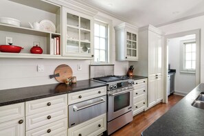 A kitchen with white cabinetry, stainless steel appliances, and a black countertop.