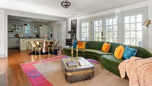 Un salón amplio con un sofá verde, una mesa de centro y un comedor al fondo.