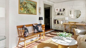 Un salon avec un banc en bois, une table basse ronde et un tableau accroché au mur.
