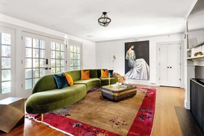 A living room with a green sofa, colorful cushions, a wooden coffee table, and a red floral rug. - Chateau Marminty (Atlanta)