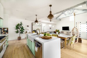 Una cocina moderna con una isla central, piso de madera e iluminación colgante.