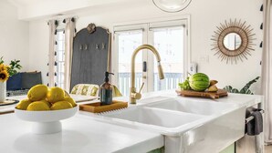 A kitchen with a white countertop, a gold faucet, and a bowl of lemons. - Penthouse Lux (Atlanta)