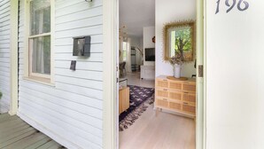 A white house with a number '196' on the wall, a mailbox, and a wicker dresser.
