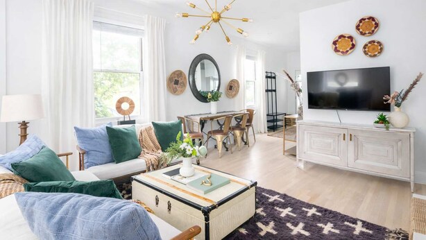 A modern living room with a sofa, coffee table, and a TV on a white cabinet.