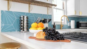 A kitchen counter with a loaf of bread, a bowl of grapes, and a container of lemons.
