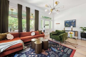 Uma sala de estar moderna com um sofá vermelho, uma poltrona verde e uma mesa de centro de vidro.