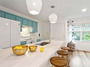 A modern kitchen with teal cabinets, white appliances, and a large island with stools.