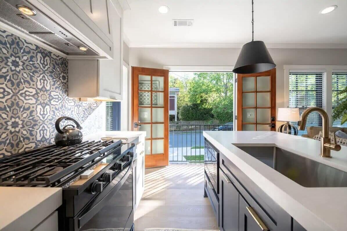 A modern kitchen with a gas stove, a large island with a sink, and a pendant light.