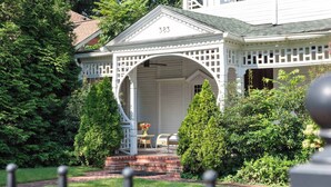 A white house with a porch and a number 383 on the roof.