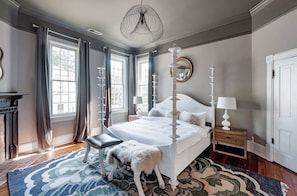 A bedroom with a large bed, a nightstand, a dresser, a mirror, and a chandelier. - Grand Damn (Atlanta)
