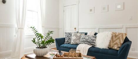 A living room with a dark blue sofa, white walls, and a wooden coffee table.
