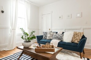 Una sala de estar con un sofá azul oscuro, paredes blancas y una mesa de centro de madera.