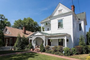 A two-story white house with a porch, a brick chimney, and a well-maintained lawn. - Buchanan (Atlanta)