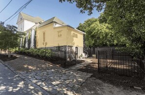 Una casa de dos pisos con un camino de piedra que lleva a la puerta principal, rodeada por una cerca de metal negro.