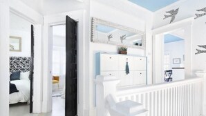 Un intérieur blanc avec un lit, une armoire bleue et une rambarde blanche.